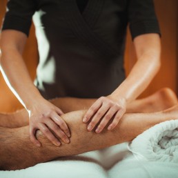 Life Physiotherapy massaging male with injurd calf muscle