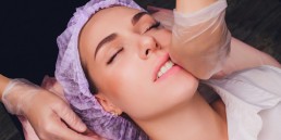 cosmetologist makes a buccal massage of the patient's facial muscles